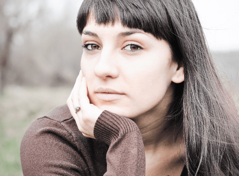 Woman resting face in hand looking at the camera